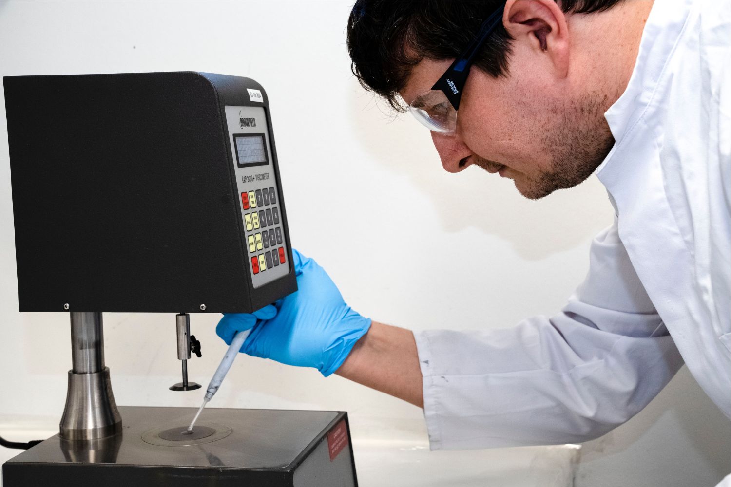 一名穿著白大褂的男子將某些物質從移液器滴到某個表面上